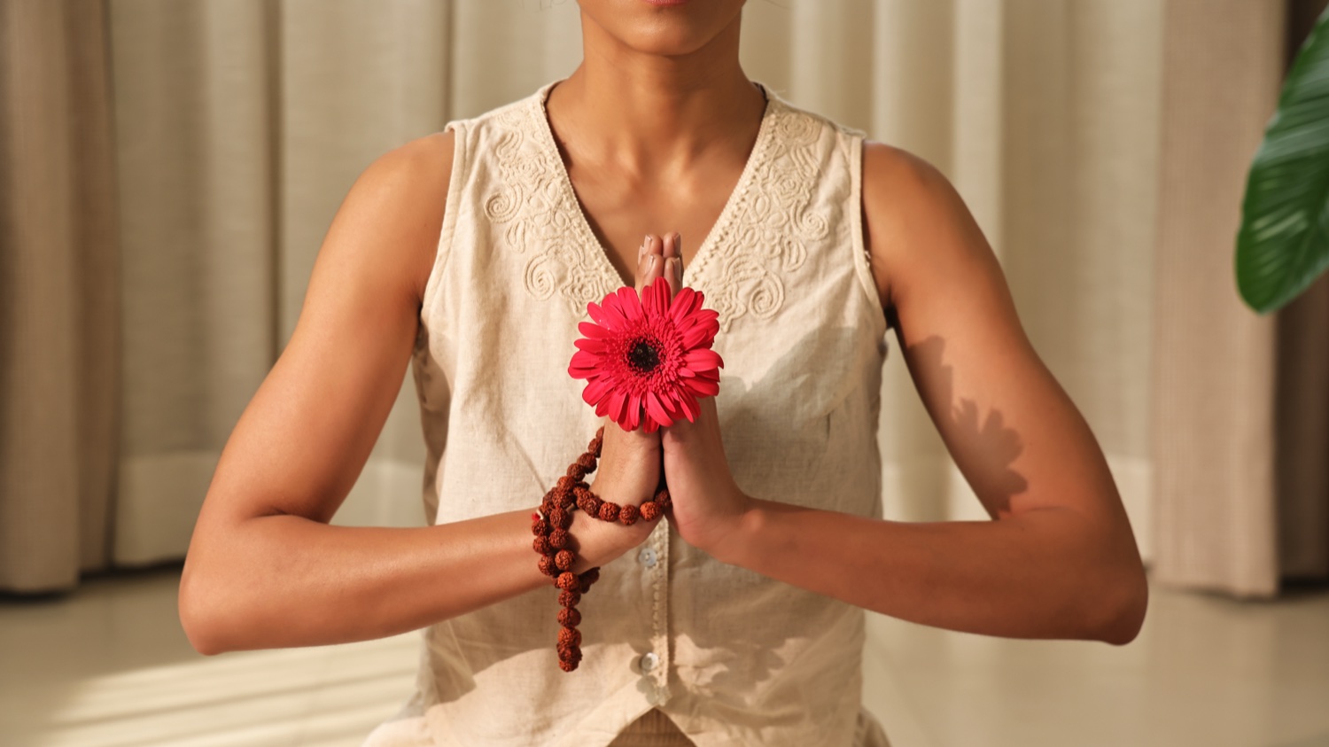 Woman holding a flower in a Namaskar gesture for Art of Vedas